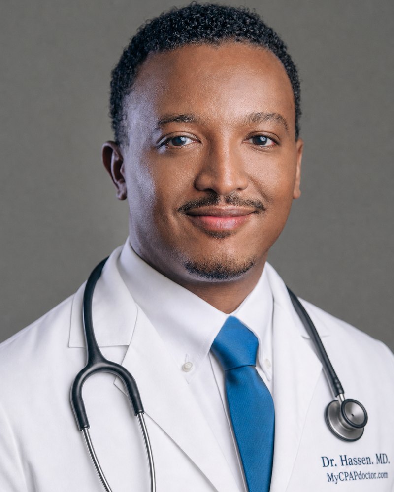 Dr. Kasim Hassen, smiling, in a navy suit and blue tie